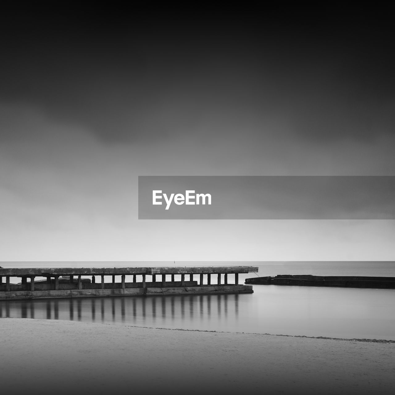 Reflection of pier in sea against sky during foggy weather