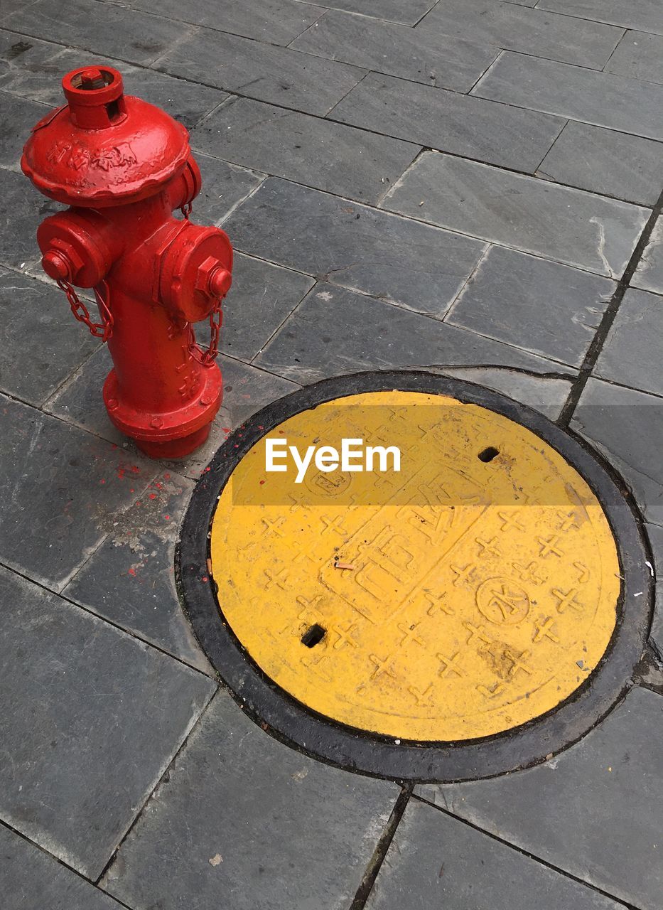 High angle view of fire hydrant by manhole on footpath