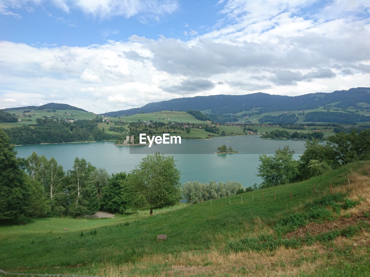 Scenic view of lake and mountains against cloudy sky