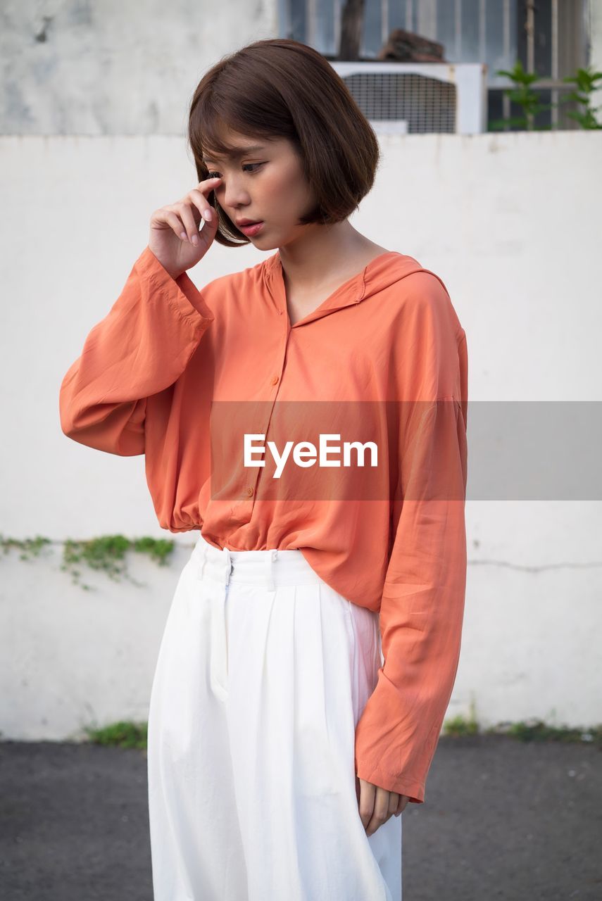 Young woman looking down while standing outdoors