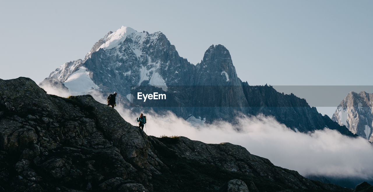 Low angle view of people climbing mountain during winter