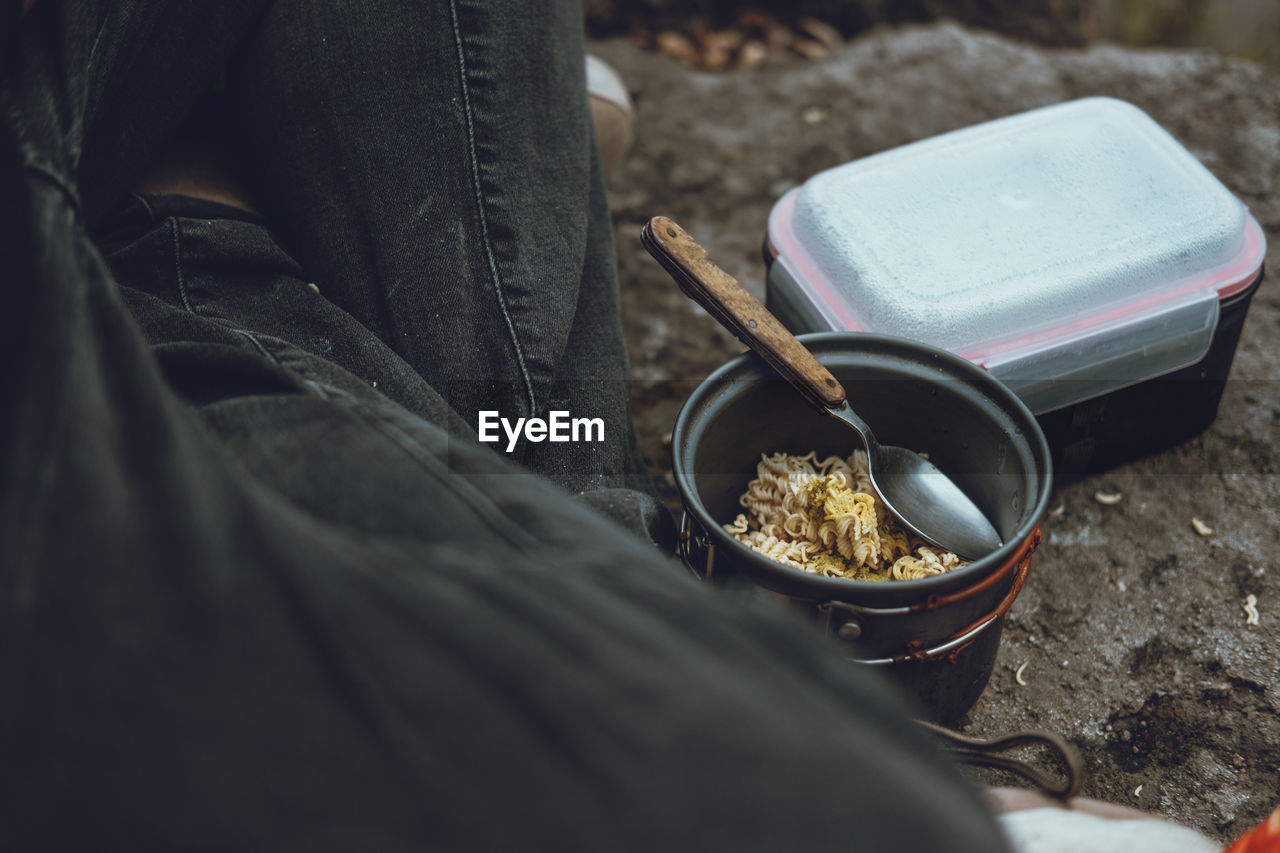 Midsection of person sitting by noodles in bowl