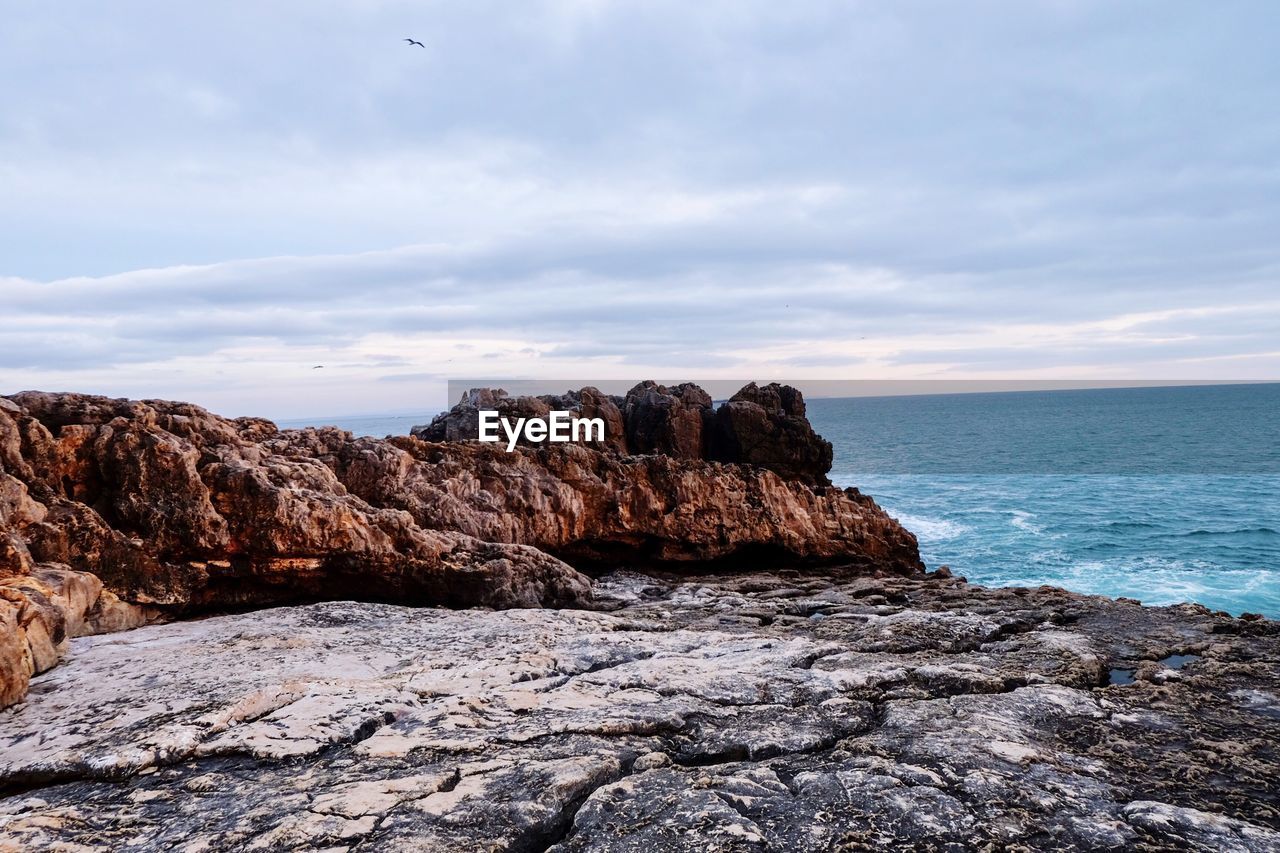 Rock formation on beach against sky