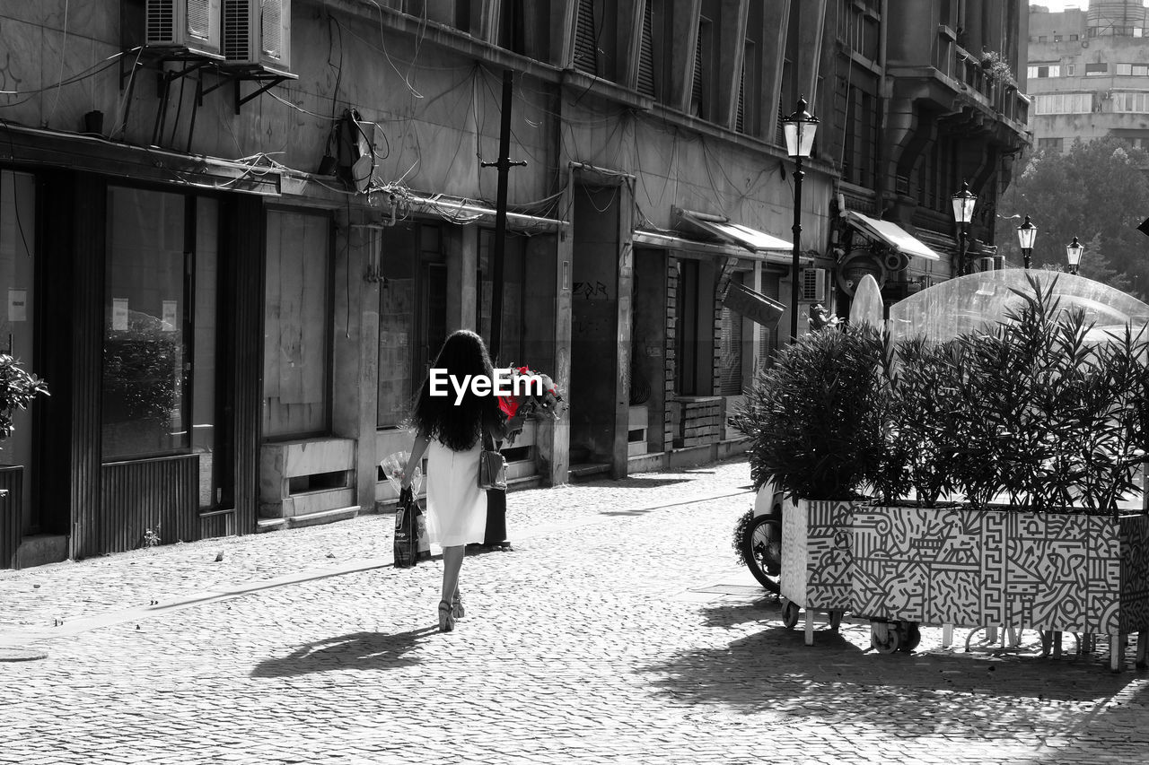 REAR VIEW OF WOMAN WALKING ON STREET