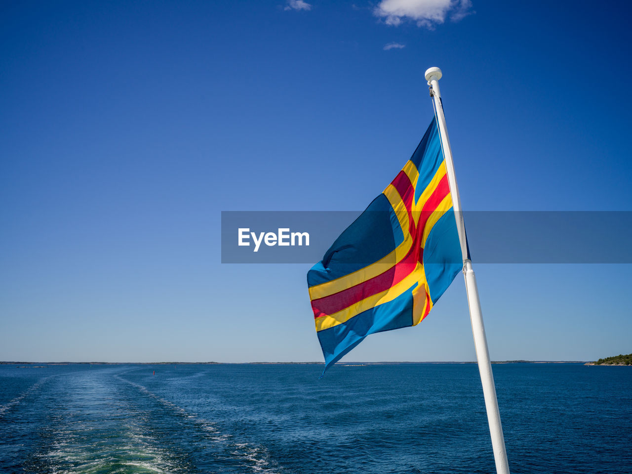Flag flags on sea against clear blue sky