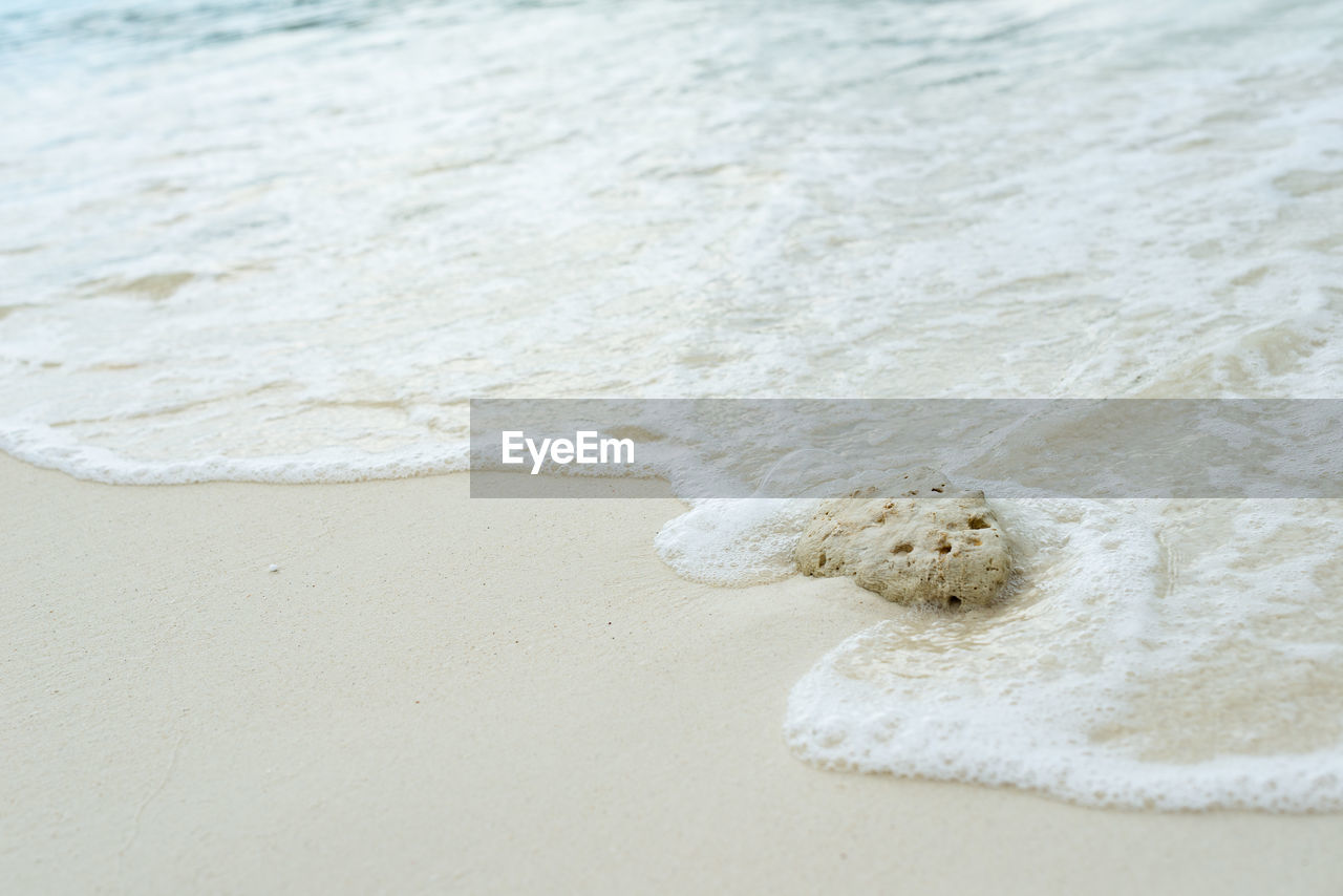 HIGH ANGLE VIEW OF SURF ON SAND