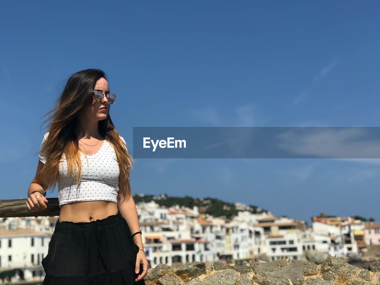 Young woman wearing sunglasses while standing on field against sky