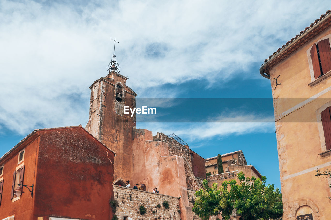 LOW ANGLE VIEW OF OLD TOWER AMIDST BUILDINGS AGAINST SKY