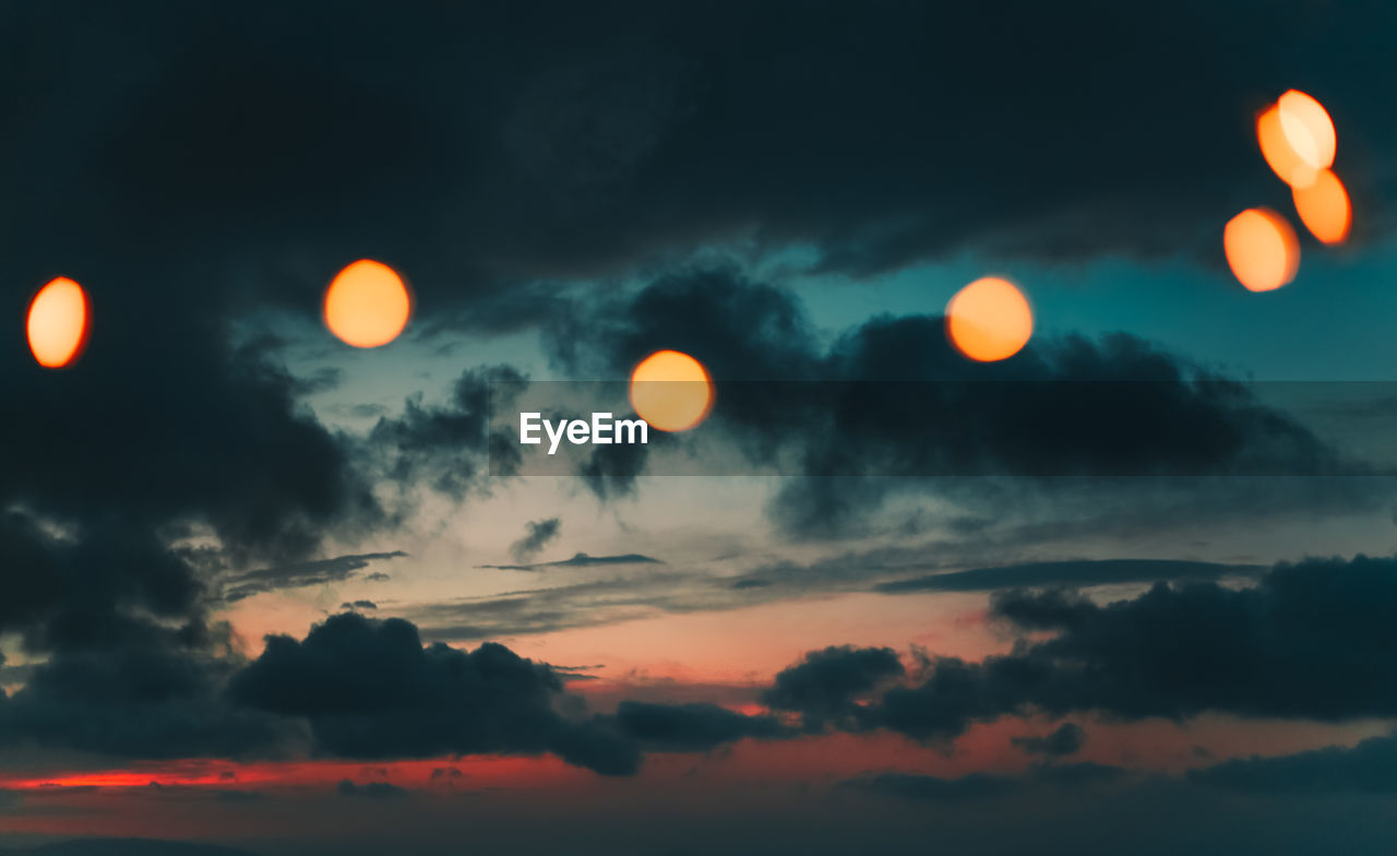 Low angle view of illuminated lights against sky during sunset