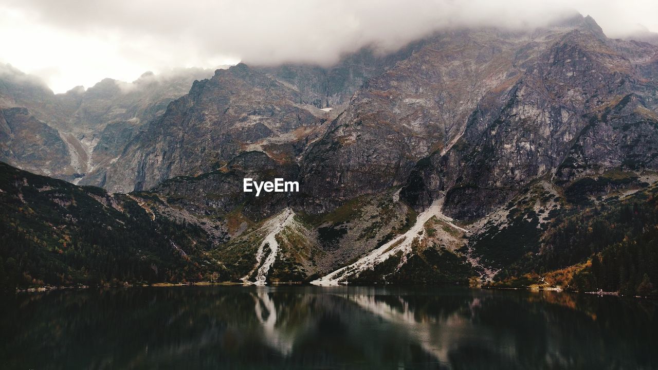 Scenic view of lake by mountains against sky