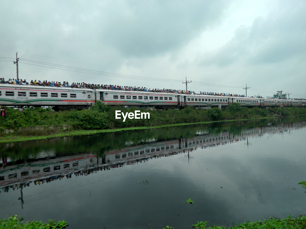 Crowd on passenger train against cloudy sky