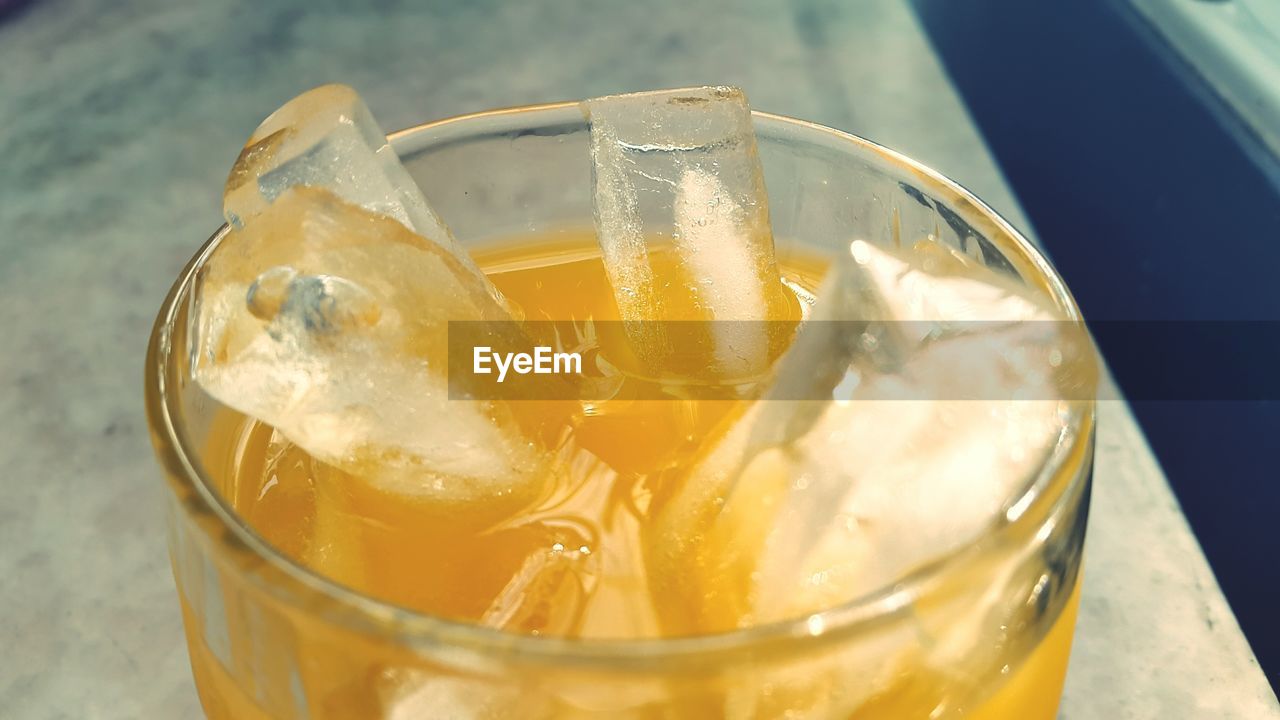 Close-up of orange juice with ice served in glass on table