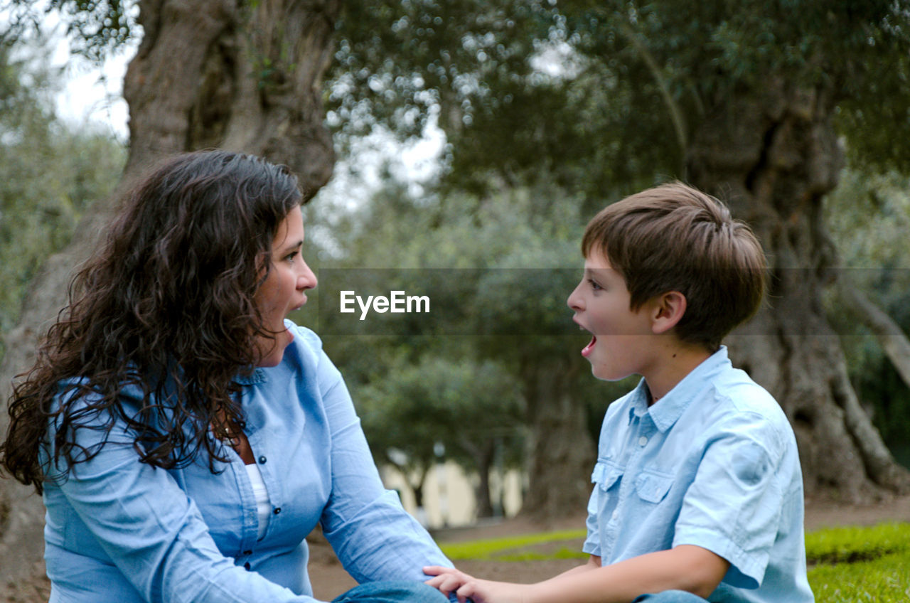 Side view of shocked mother and son against trees