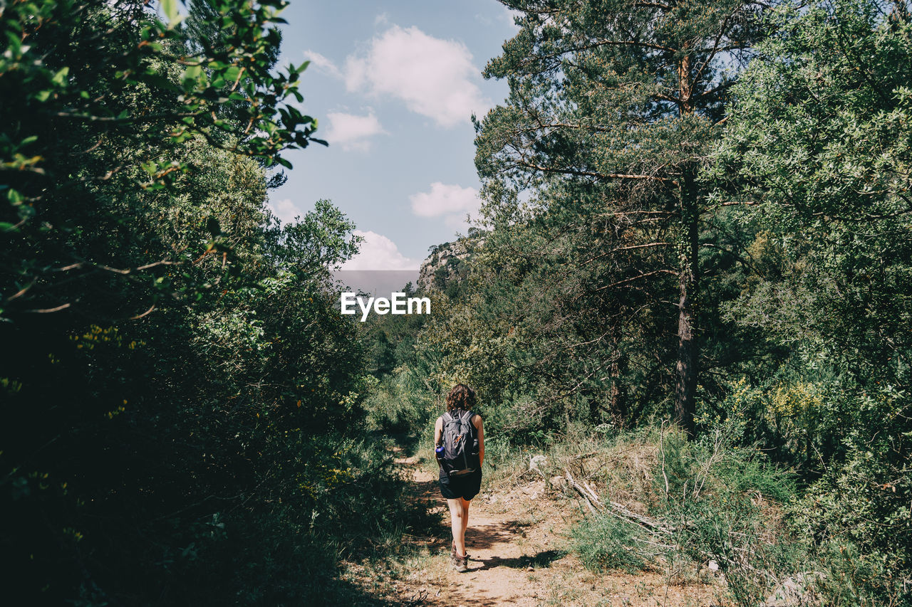 Girl walking along a small path in the mountain of prades, tarragona, spain. on a sunny summer day