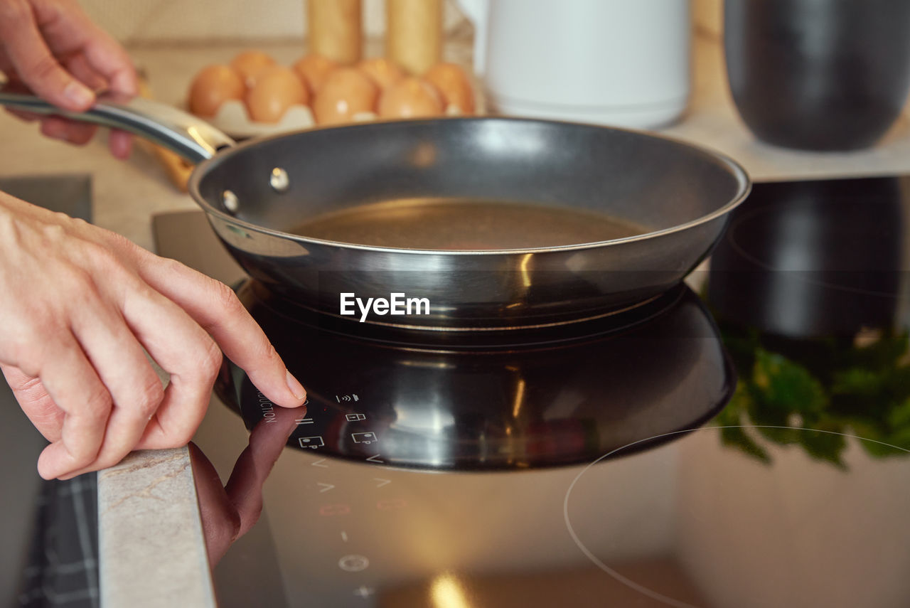 Woman turn on induction hob with frying pan