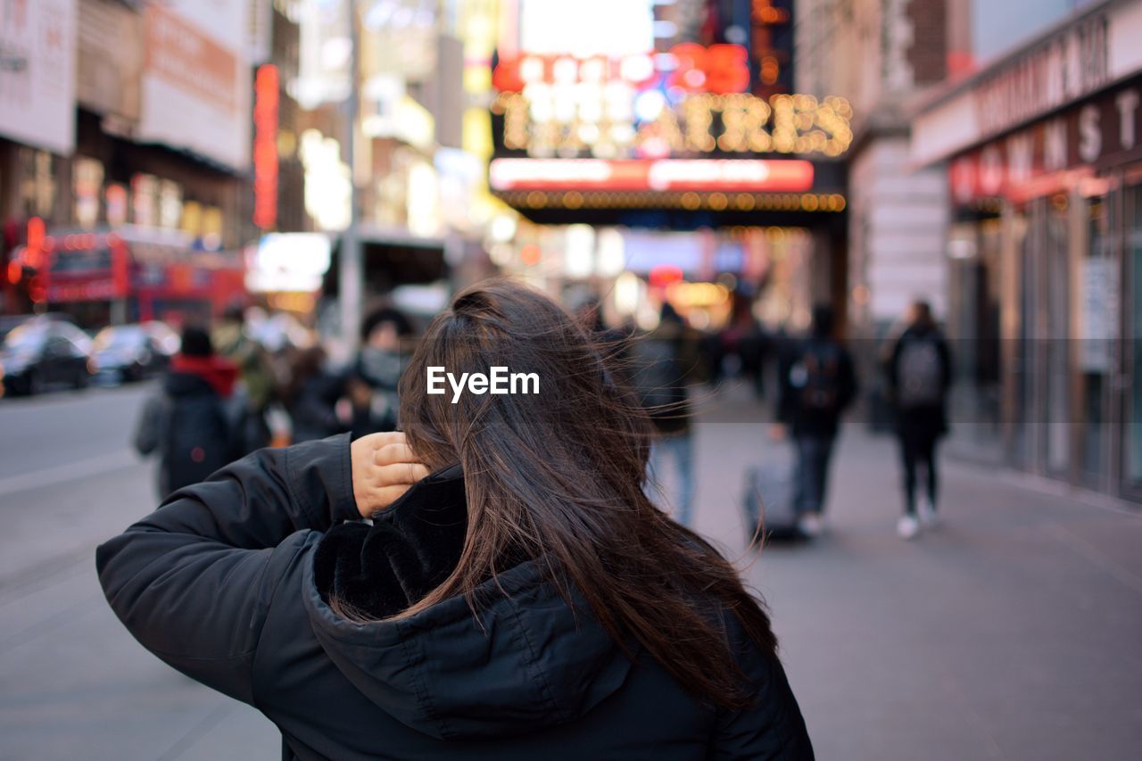 REAR VIEW OF WOMAN AGAINST CITY