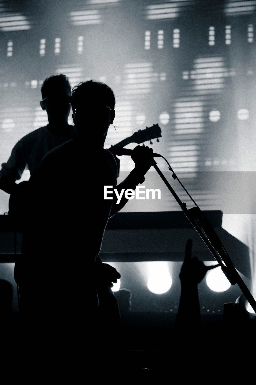 Silhouette singer and guitarist performing during music concert