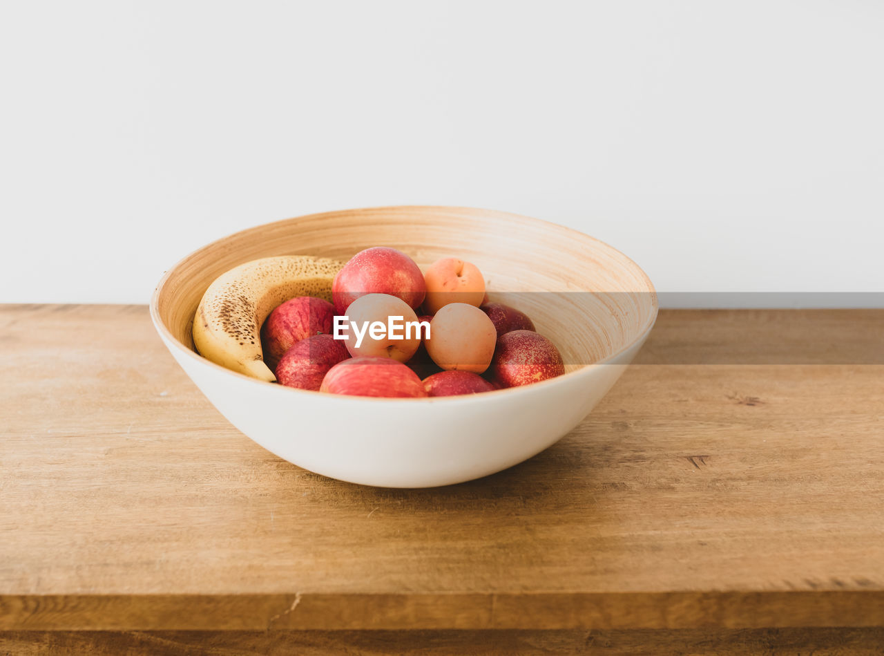 High angle view of fruits in bowl on table against white background