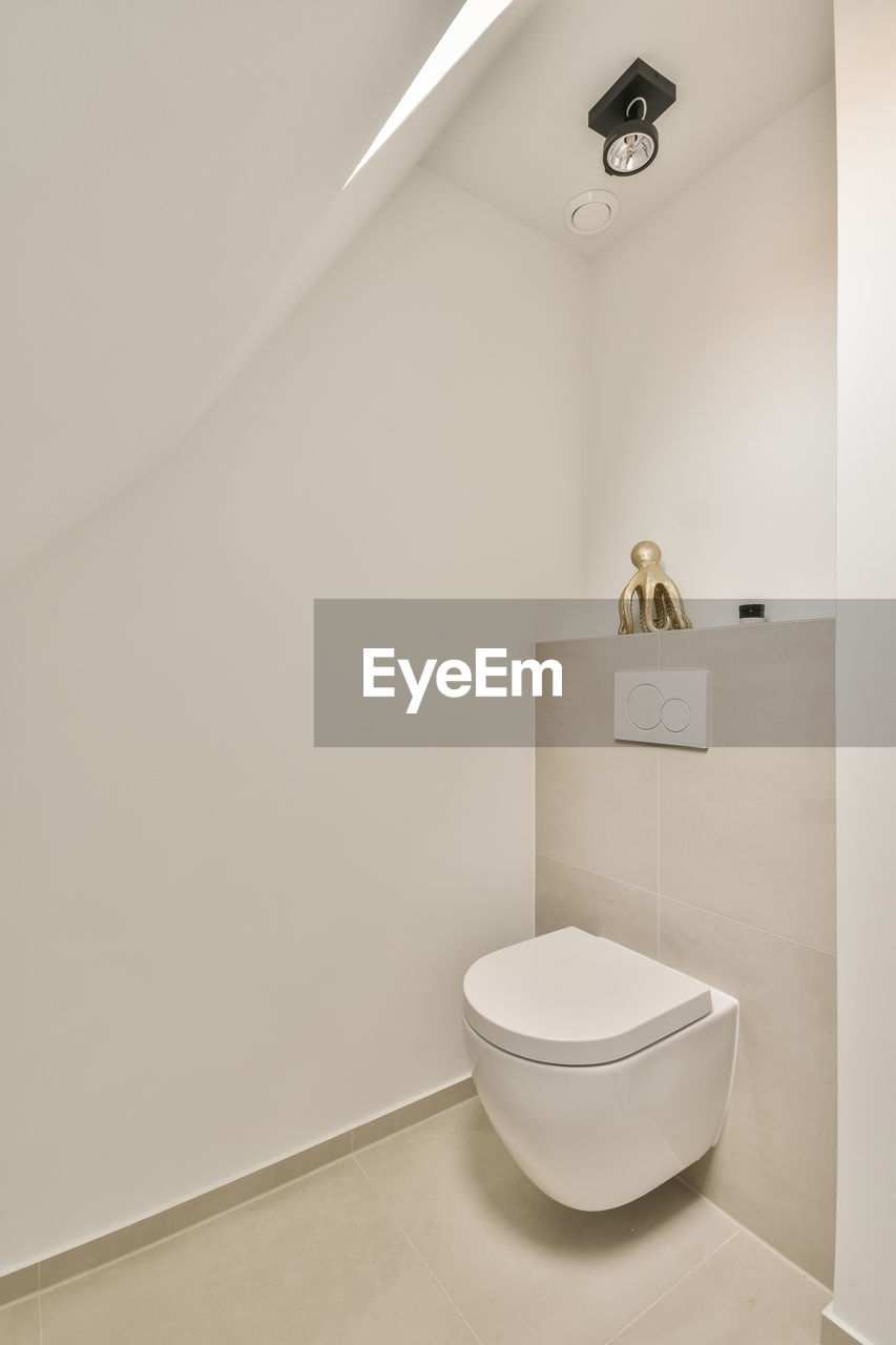 Contemporary bathroom interior with toilet bowl on tiled wall in light house