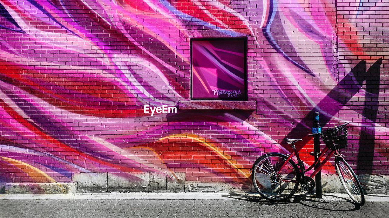 Bicycle parked on sidewalk against colorful house