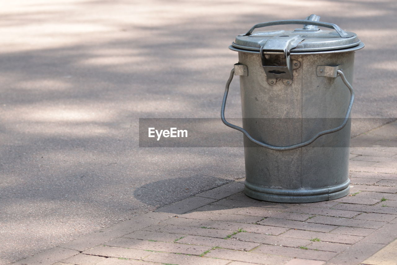 Metal garbage can on sidewalk