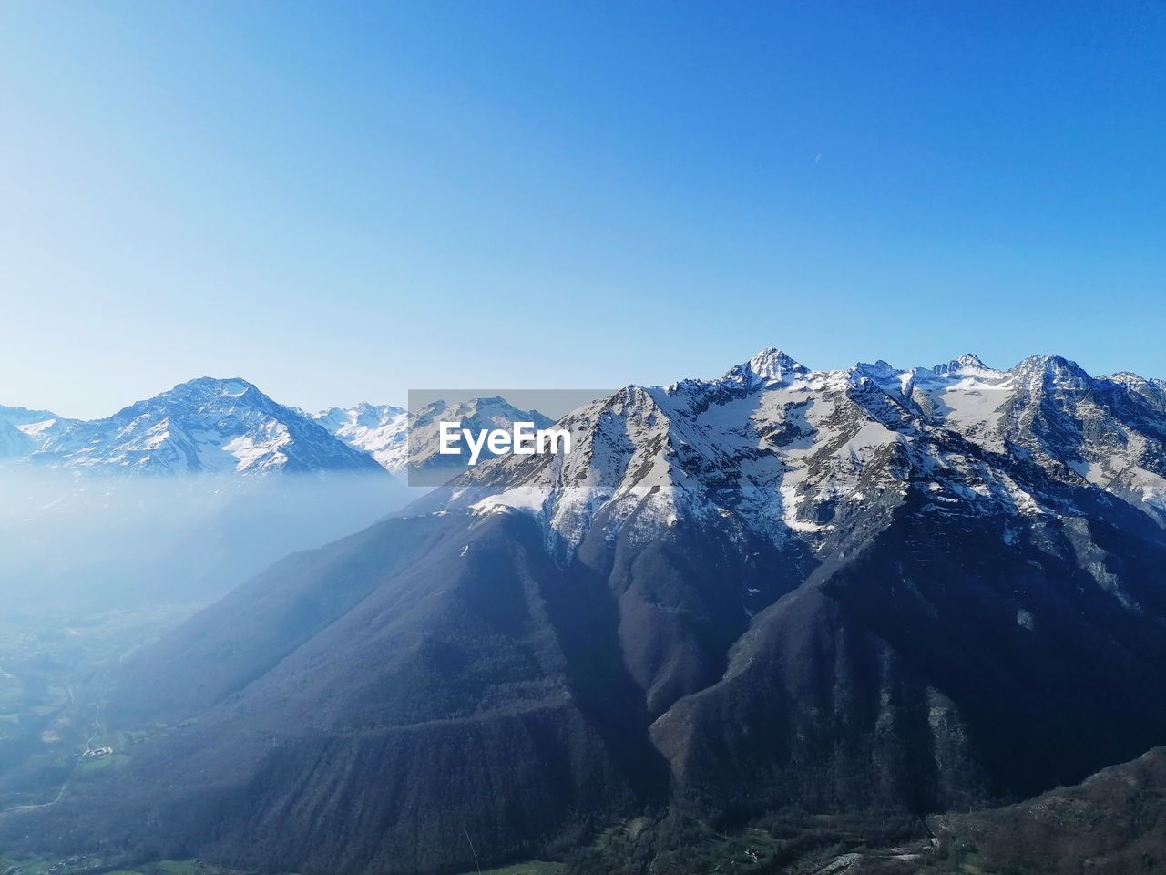 Scenic view of snowcapped mountains against clear blue sky