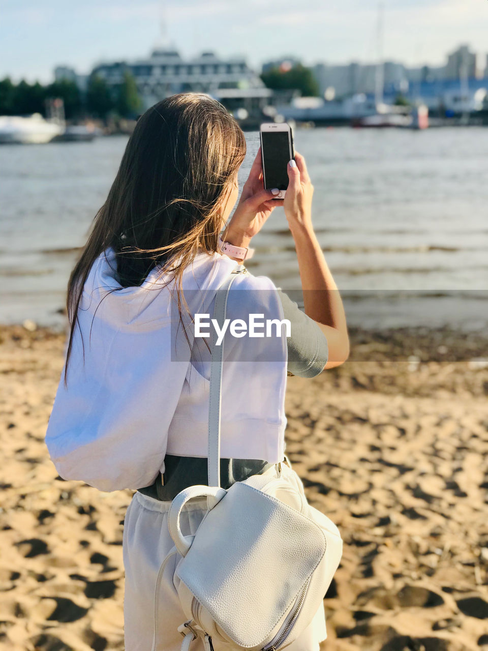 Rear view of woman photographing on beach