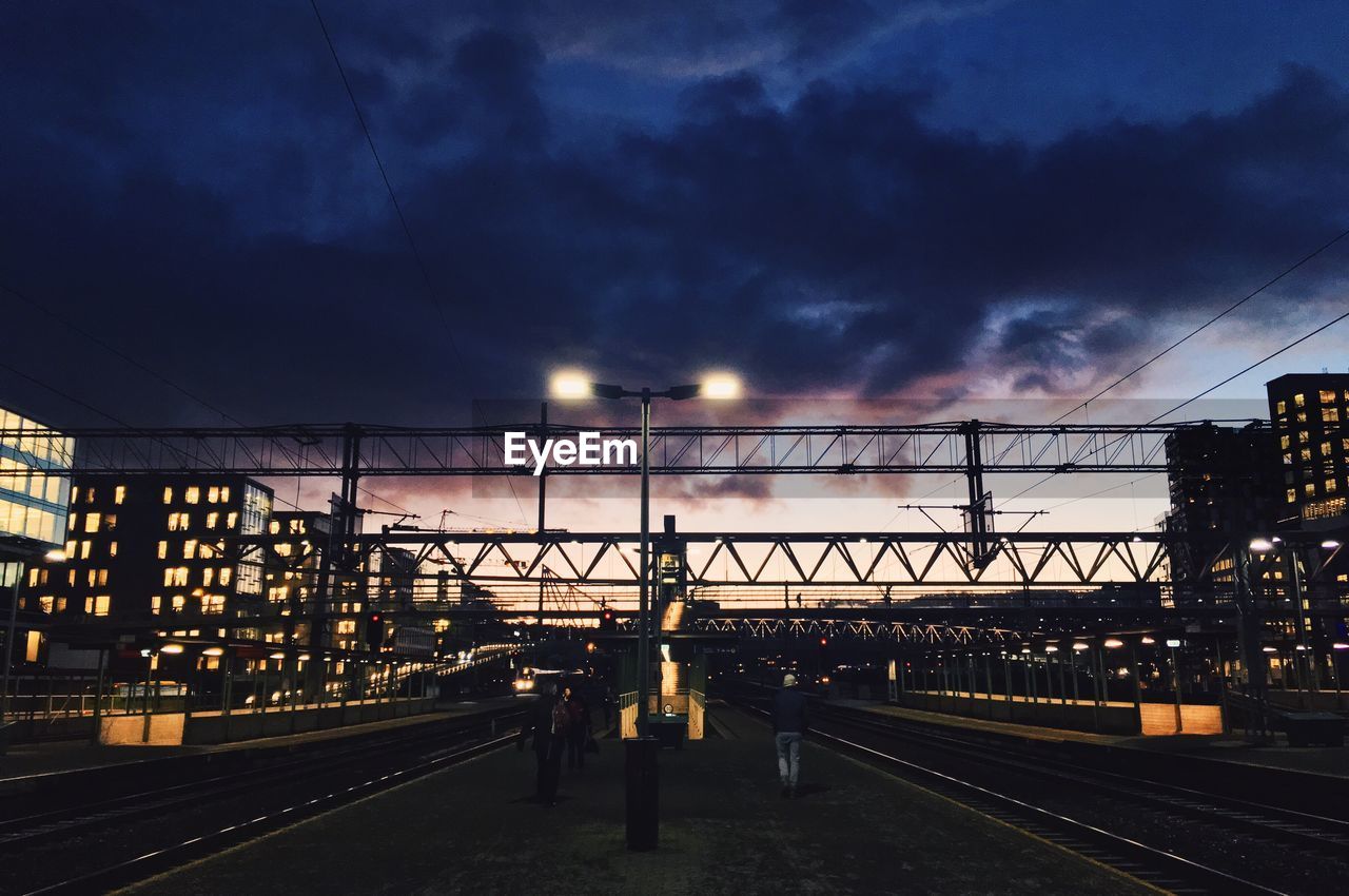 RAILWAY TRACKS AT RAILROAD STATION AGAINST SKY
