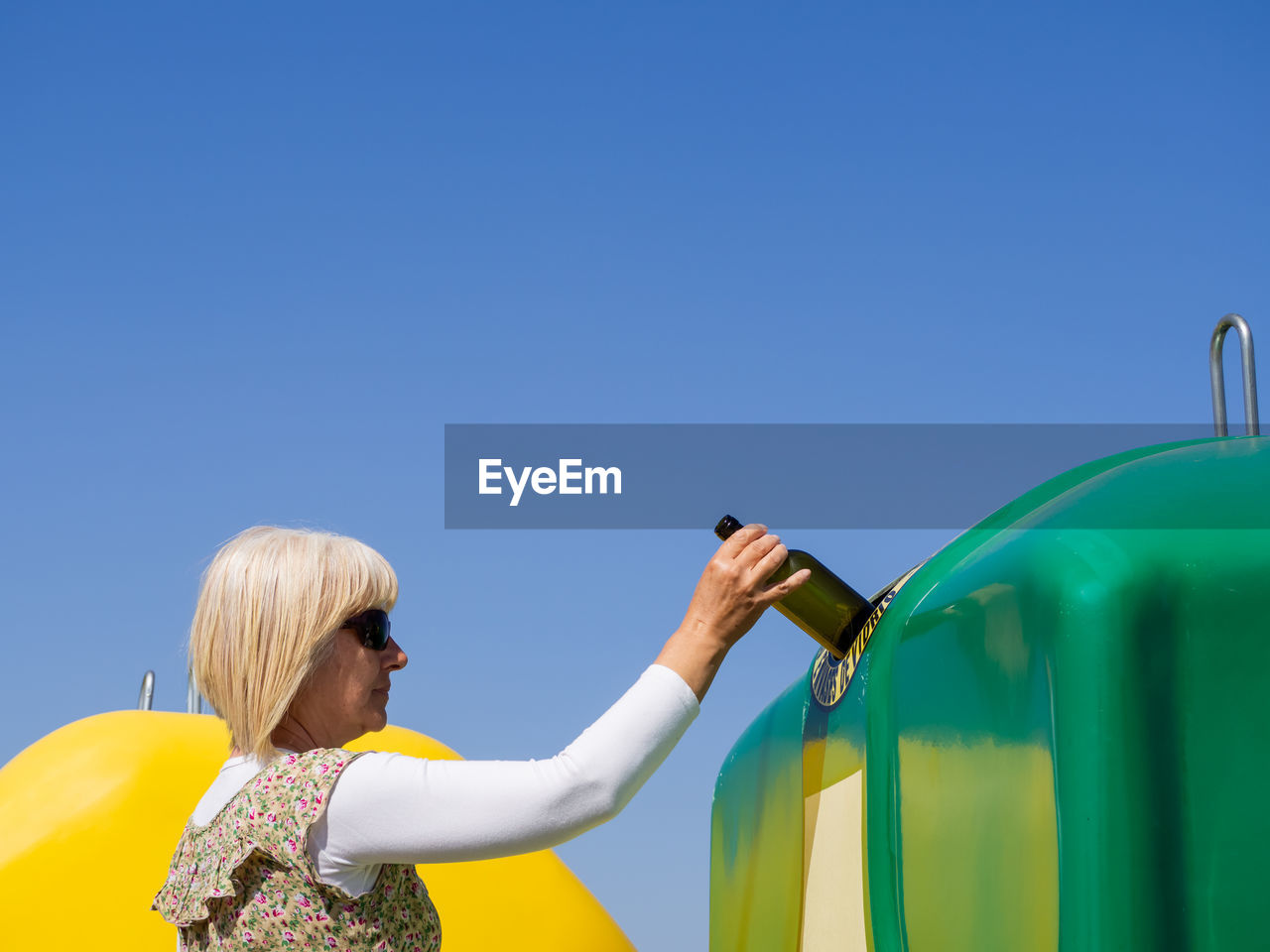 REAR VIEW OF WOMAN HOLDING BLUE UMBRELLA AGAINST CLEAR SKY