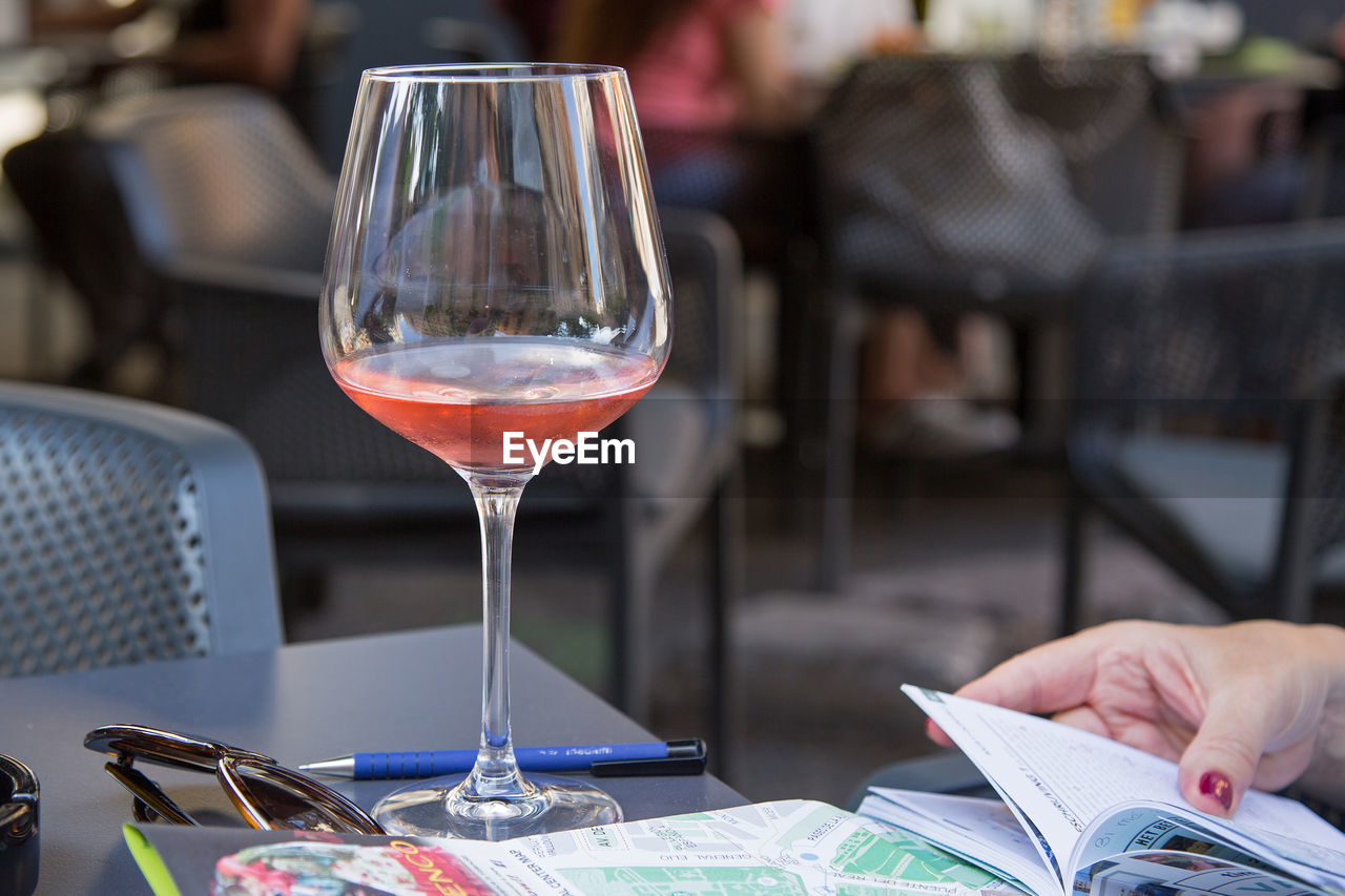 CLOSE-UP OF HAND HOLDING WINE GLASSES ON TABLE