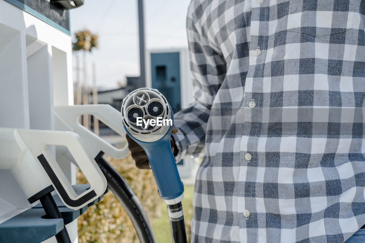 Man with electric car charger at station