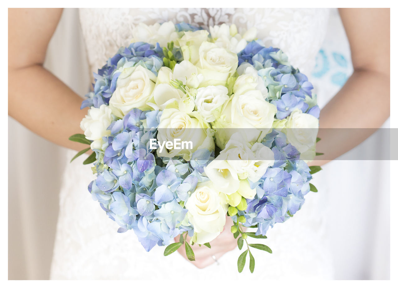 Midsection of bride holding flower bouquet