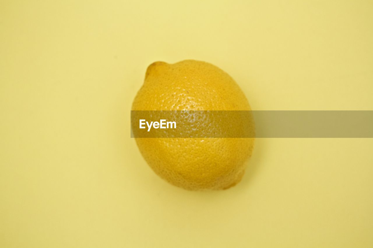 Close-up of lemon on yellow background