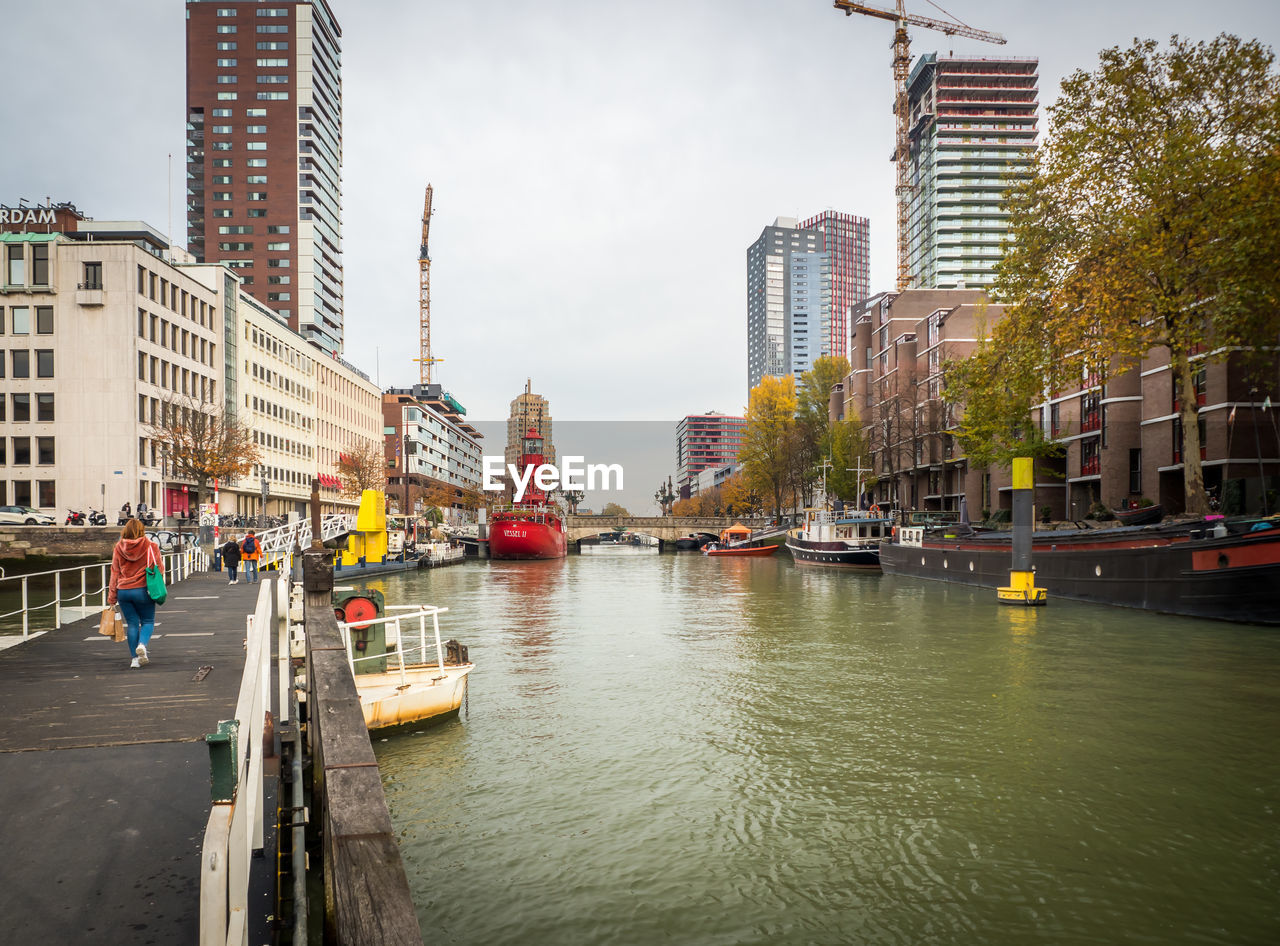 Boats in river by buildings in city against sky