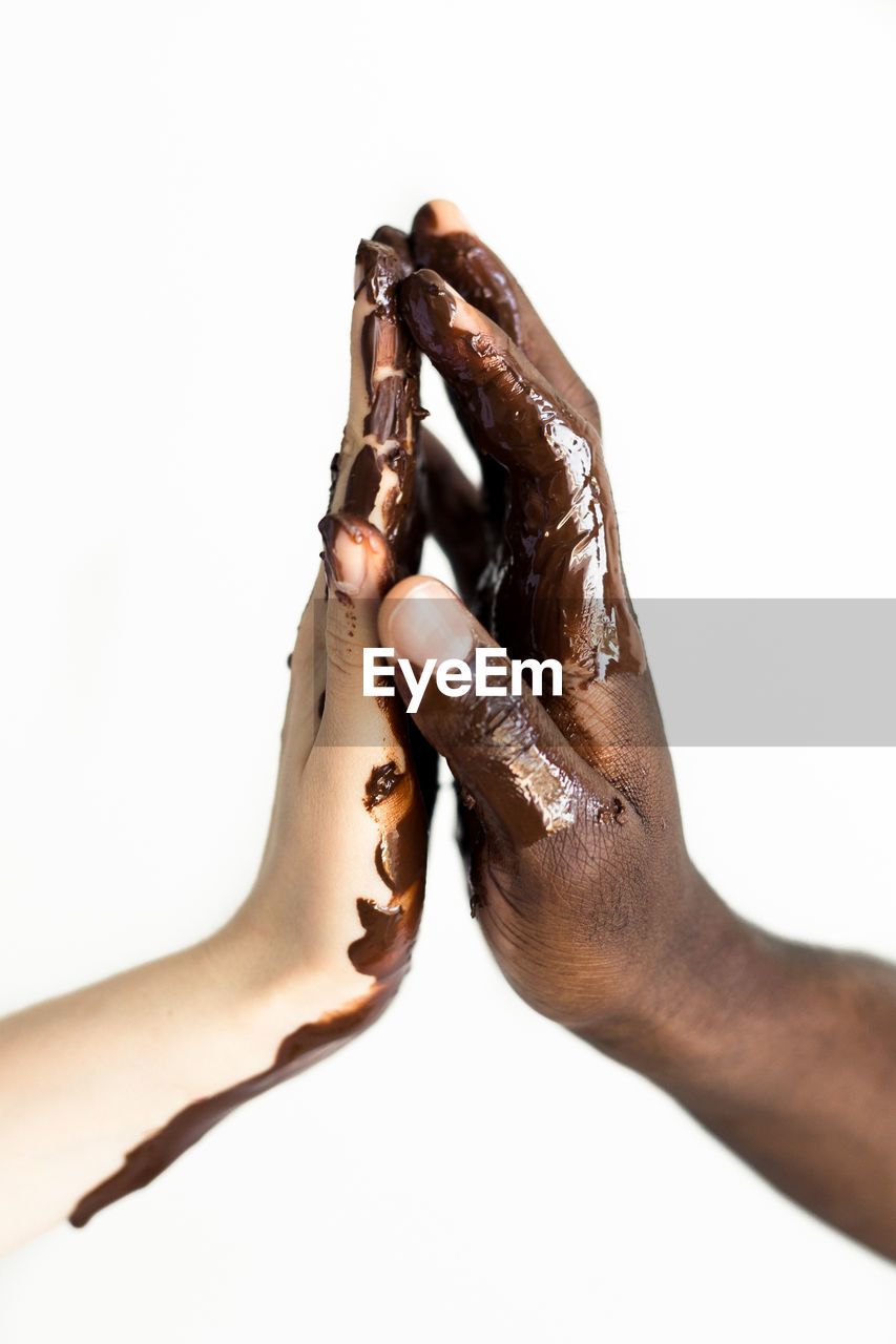Cropped messy hands of couple touching against white background