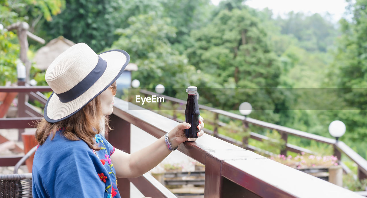 Rear view of woman with hat on railing