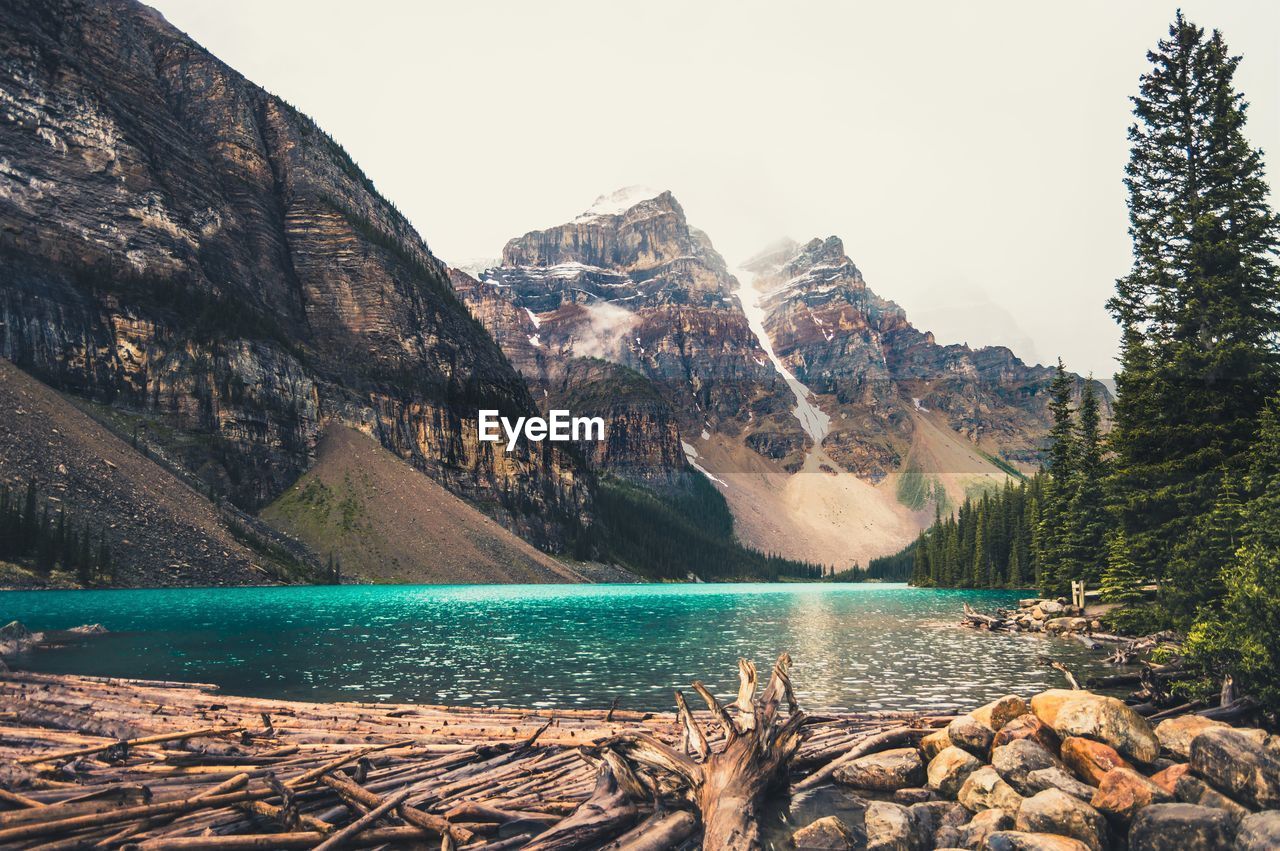 Scenic view of river and rocky mountains against clear sky