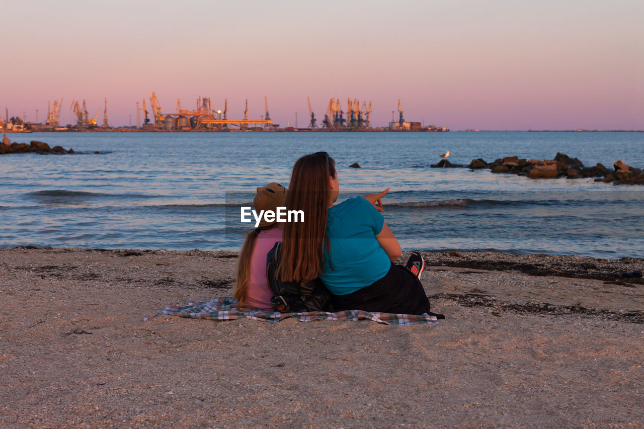 Girl staycation picnicking on sea sand beach with sunset background. local travel. evening seascape.