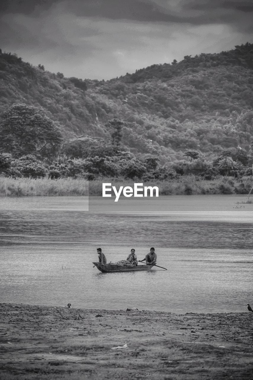 People in boat on sea against mountain