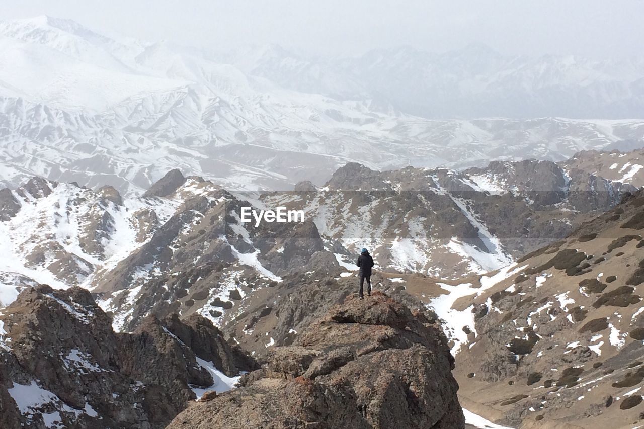 Rear view of person standing on mountain during winter