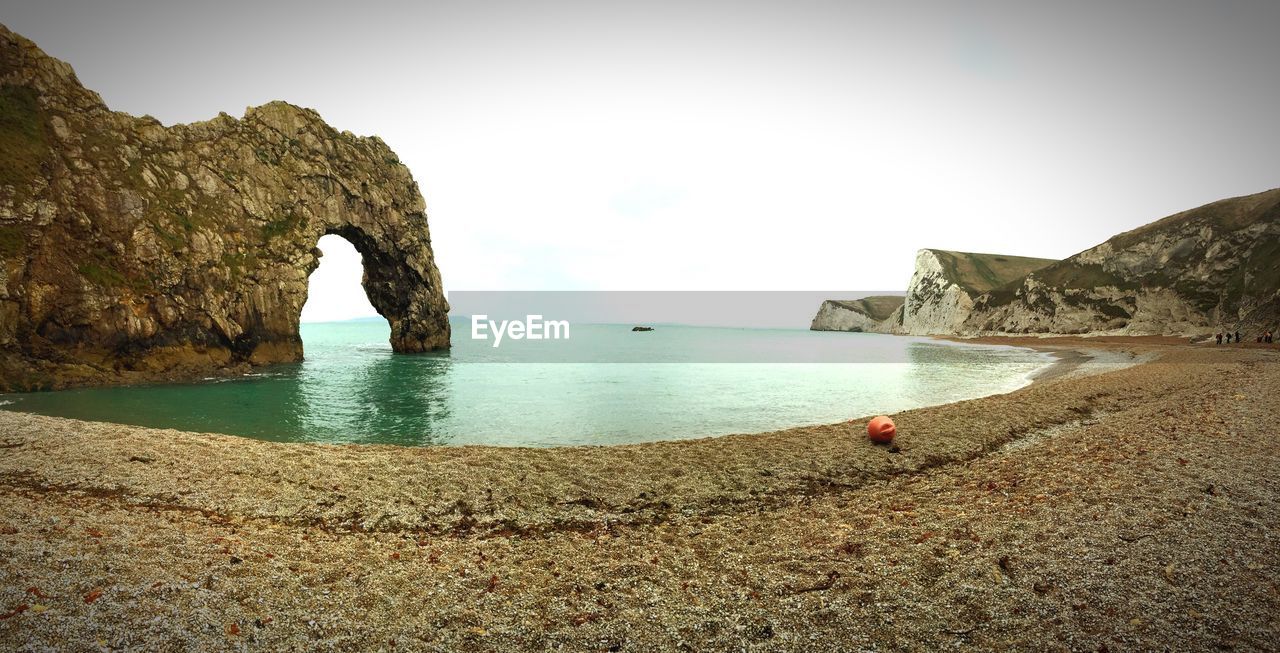 ROCK FORMATION BY SEA AGAINST CLEAR SKY