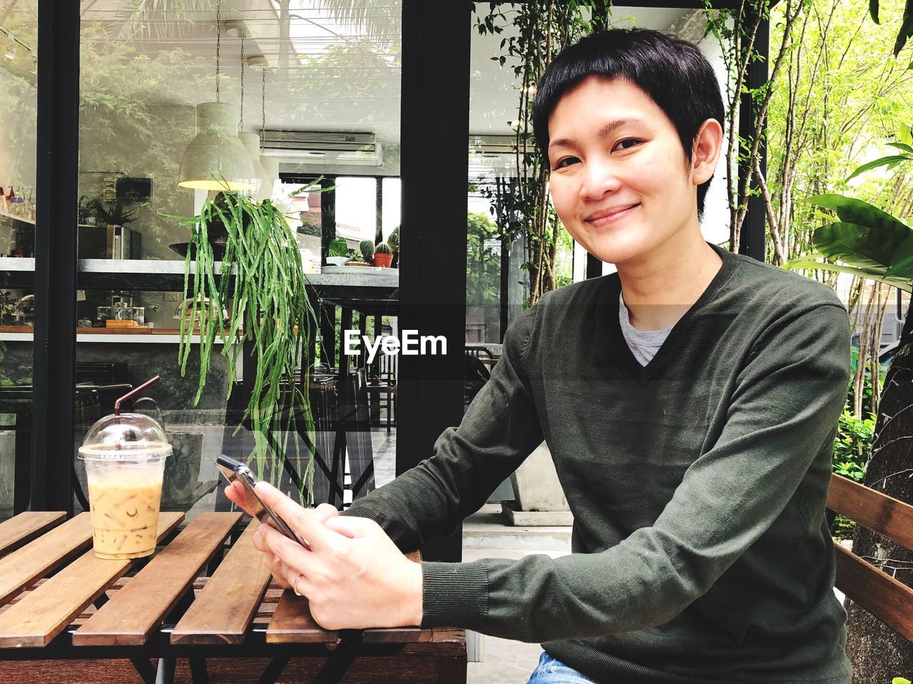 Portrait of smiling woman using mobile phone at cafe