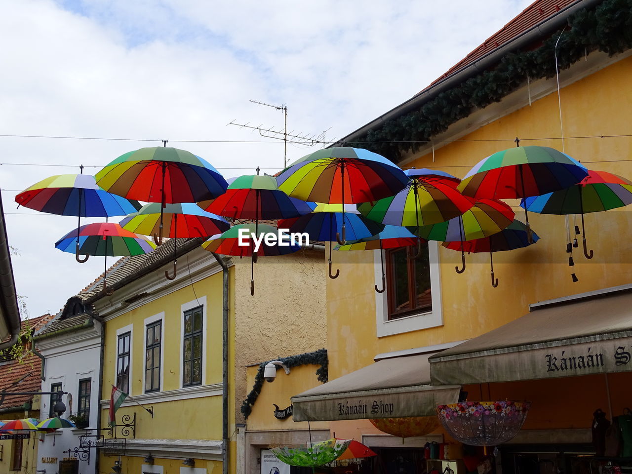 Low angle view of multi colored umbrellas hanging against buildings