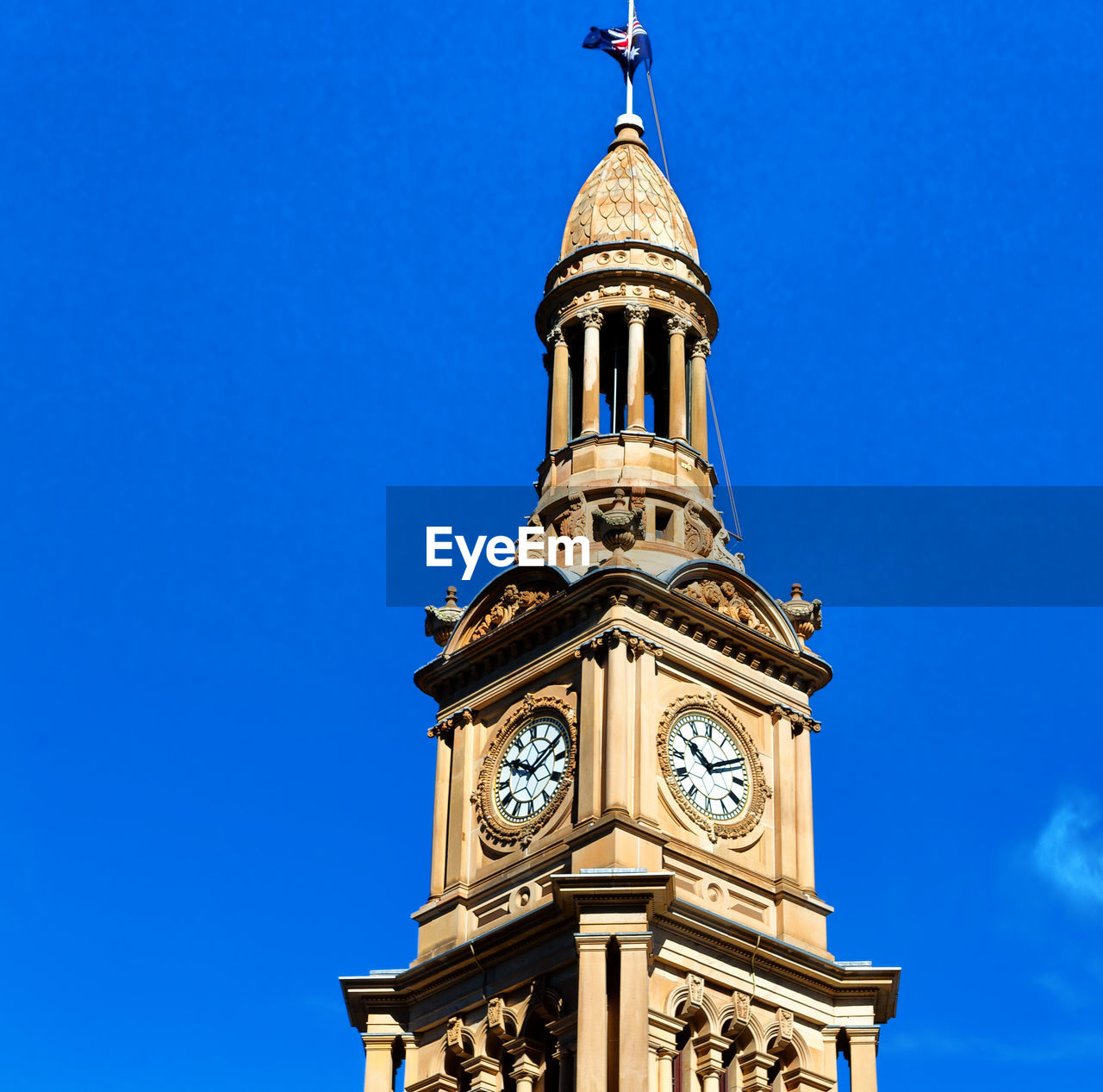 LOW ANGLE VIEW OF CLOCK TOWER AGAINST BLUE SKY AND BUILDING