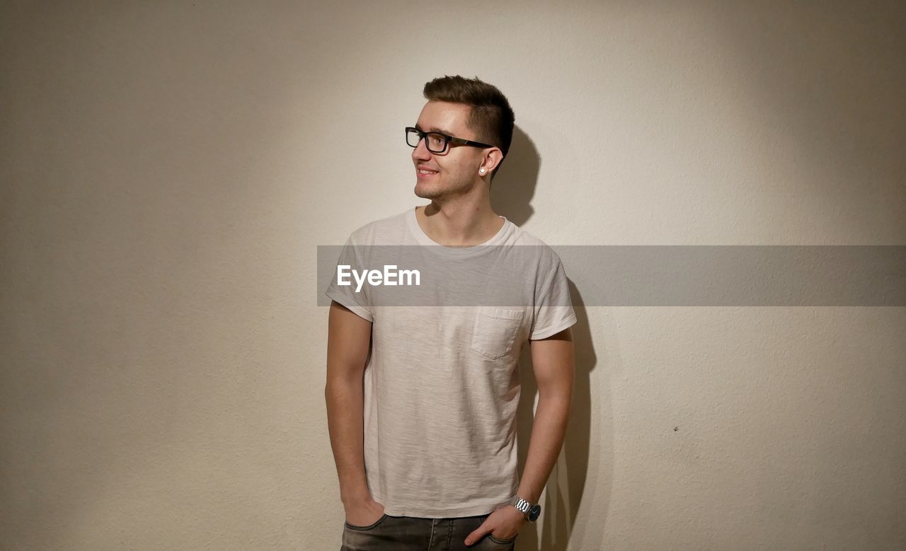 Handsome man standing against white wall