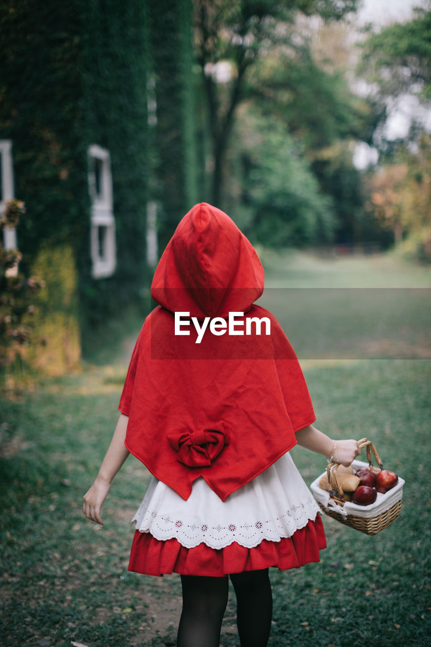 Rear view of girl holding basket on field