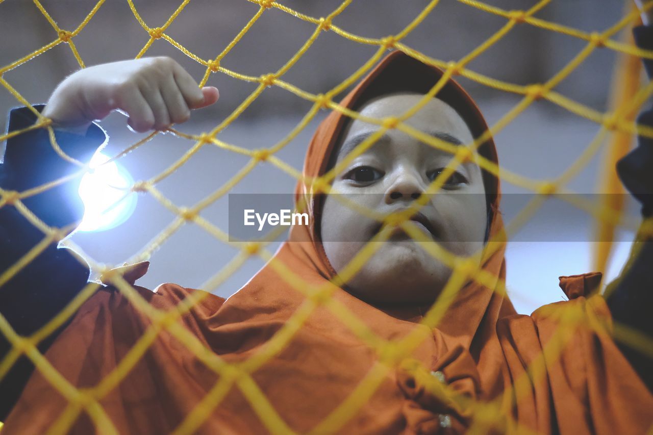 Portrait of girl wearing hijab seen through metal fence