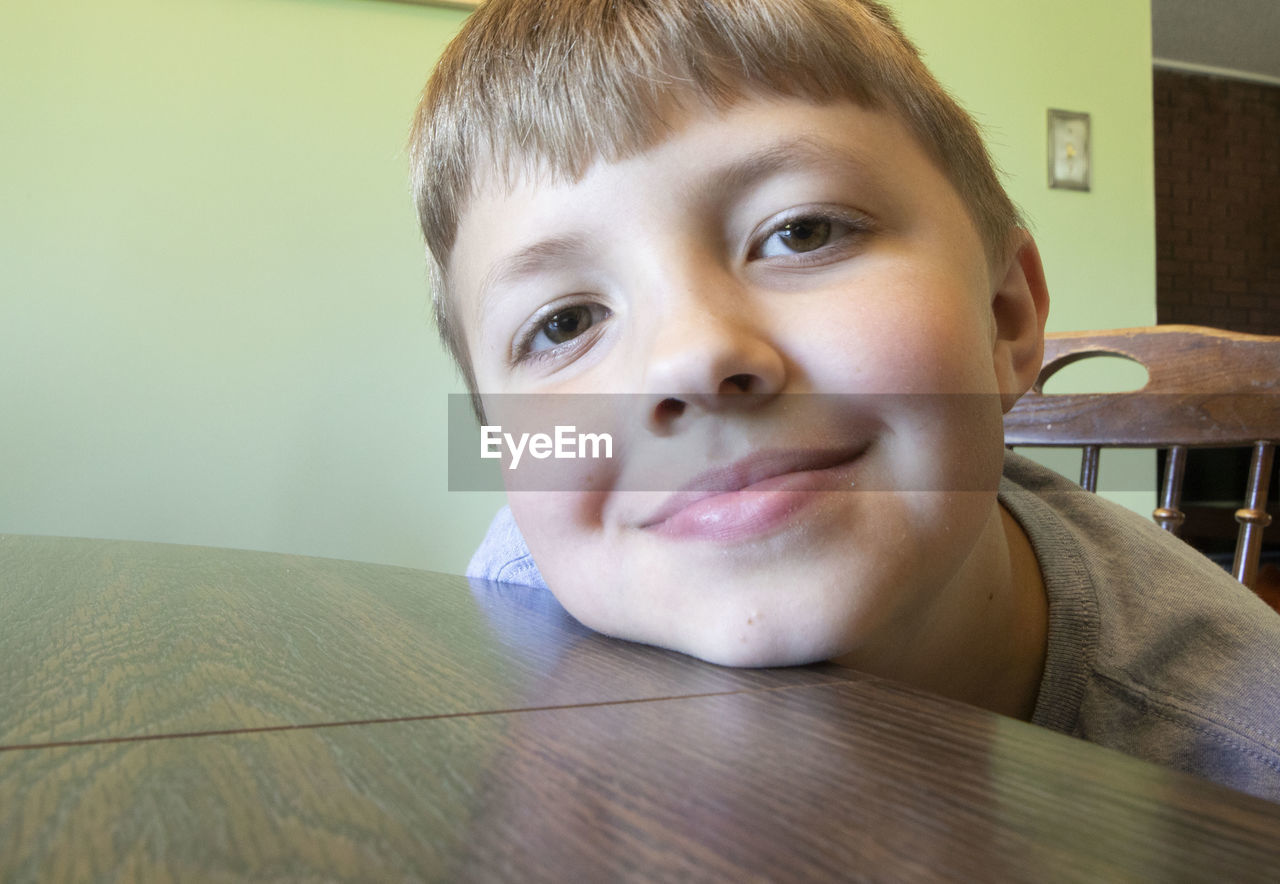 CLOSE-UP PORTRAIT OF SMILING BOY WITH TABLE