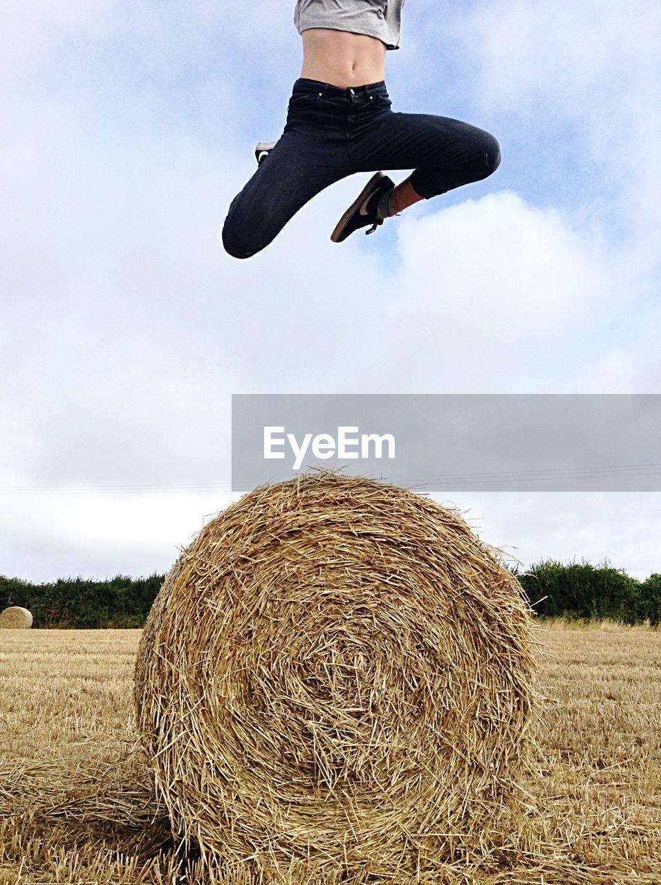 MAN JUMPING IN FIELD AGAINST SKY