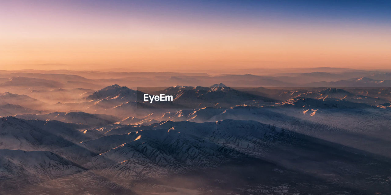 Scenic view of snow covered mountains against sky during sunset